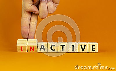 Active or inactive symbol. Businessman turns wooden cubes and changes the word Inactive to Active. Beautiful orange table orange Stock Photo
