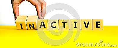 Active or inactive symbol. Businessman turns wooden cubes and changes the word Inactive to Active. Beautiful yellow table white Stock Photo
