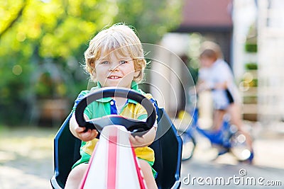 Active little child driving pedal car in summer garden Stock Photo