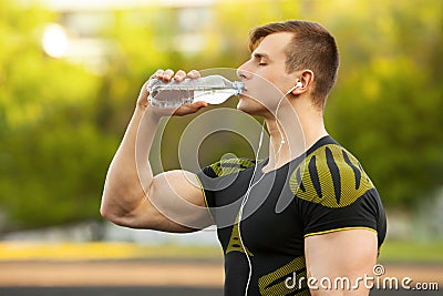 Active man drinking water from a bottle, outdoor. Muscular male quenches thirst Stock Photo