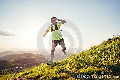 Active mountain trail runner dressed bright t-shirt with a backpack in sports sunglasses running endurance ultramarathon race by Stock Photo