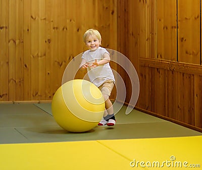 Active preschool boy playing with big ball in indoor sports hall/gym class Stock Photo