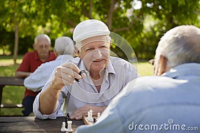 Active retired seniors, two old men playing chess at park Stock Photo
