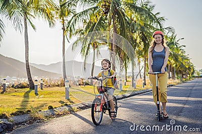 Active school kid boy and his mom in safety helmet riding a bike with backpack on sunny day. Happy child biking on way Stock Photo