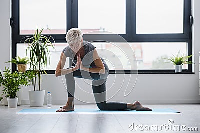 Active senior woman practicing yoga indoors Stock Photo