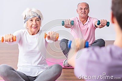 Active seniors during exercises on gym with young instructor Stock Photo