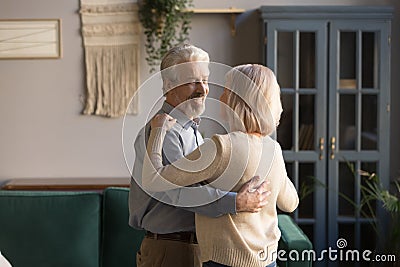 Grey-haired husband embraces blond wife couple dancing at home Stock Photo