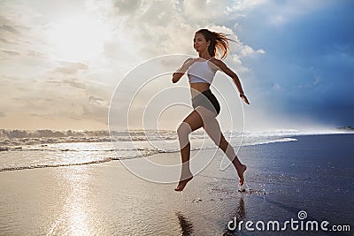 Active sporty woman run along sunset ocean beach. Sports background. Stock Photo