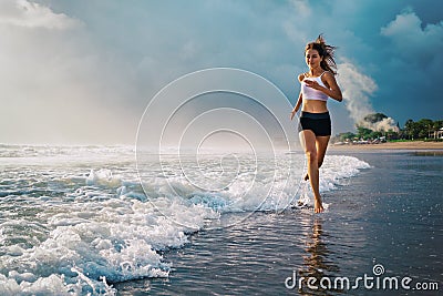 Active sporty woman run along sunset ocean beach. Sports background. Stock Photo