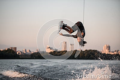 active strong man rider holds rope and making extreme jump showing trick on wakeboard. Stock Photo