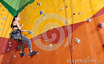 Active woman climbing up the wall in gym Stock Photo