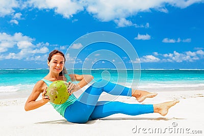 Active woman doing sports exercises with coconuts on sea beach Stock Photo