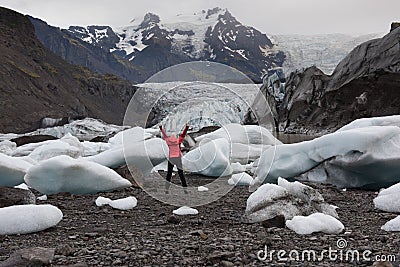 Active Woman jumping in bright red raincoat near the Glacier Lagoon Stock Photo