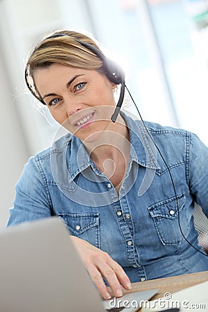 Active woman teleworking from home with headphones Stock Photo