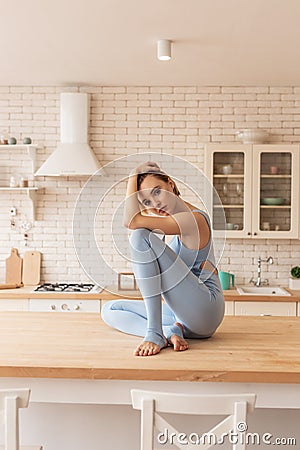 Appealing young lady in light blue outfit sitting in tragic posture Stock Photo