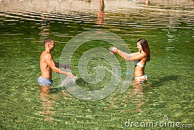 Active young couple plays in shallow water on a hot summer morning Stock Photo