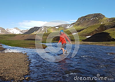 Active young hiker woman crossing river and enjoying the mountain view on adventure active freedom emotions vacations outdoor Stock Photo