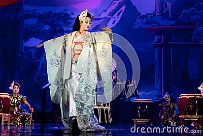 Actress in traditional white kimono with long sleeves and fox mask dancing Stock Photo