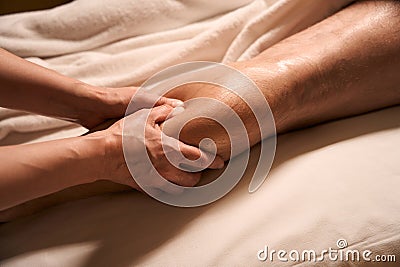 Acupressure practitioner pressing on acupoint on customer calf using thumbs Stock Photo