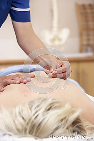 Acupuncturist treating female client Stock Photo