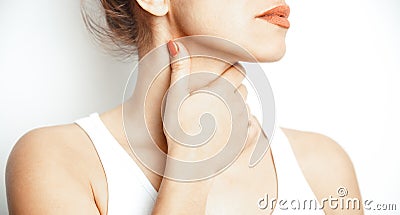 Acute pain in throat, close-up. Young woman holds her hand on her throat, on a white background. Pain area of red color Stock Photo