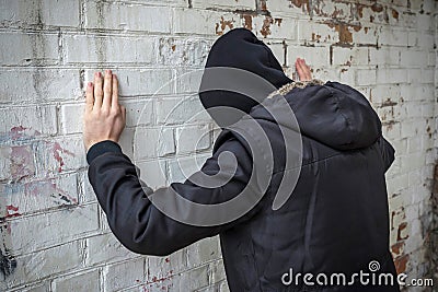 Addict alone in an abandoned building, against a white brick wall. Side view. Stop dope Stock Photo