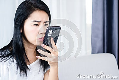 Social addiction concept with addicted Asian woman forcing her eyes looking at the screen of mobile phone Stock Photo