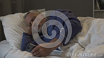 Addicted to smartphone retired man scrolling application instead of sleeping Stock Photo