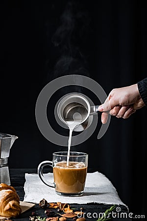 Pouring steaming milk into a cup of coffee Stock Photo