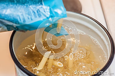Adding pasta to boiling water from the packaging Stock Photo