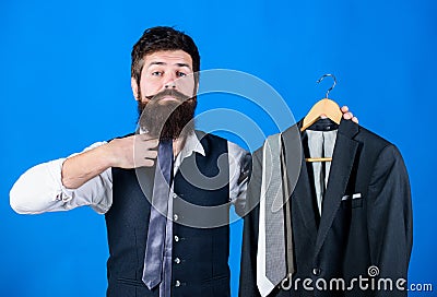 Adding a tie to his look. Hipster matching silk necktie to his bearded face. Brutal hipster holding necktie collection Stock Photo