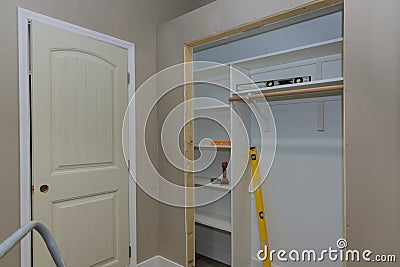 Adding a white melamine shelf to the interior of a clothing closet in which there are several empty shelves left to make Stock Photo