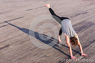 Adho Mukha Svanasana practiced by a young outdoor yoga enthusiast in the city Stock Photo