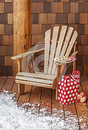 Adirondack chair with Christmas gifts on the snowy wooden porch deck of a rustic country cabin. Winter holiday vacation homes. Stock Photo