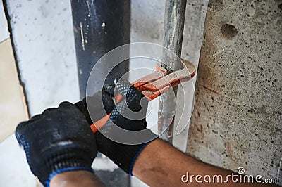 Adjustable wrench, plumbing, pipe, hand in a work glove, efforts to unscrew the water pipe Stock Photo
