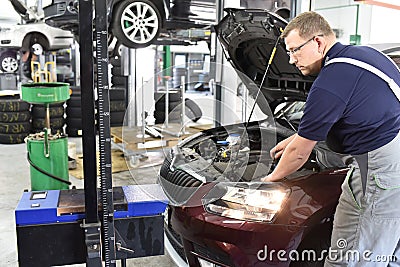 Adjusting the headlights on the car by mechanics in a garage Stock Photo