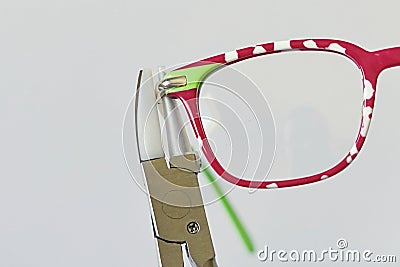 Adjusting inclination on patchy red and white children eyeglass frame. Stock Photo