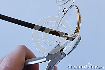 Adjusting inclination of temples on modern metal eyeglass frame with conical inclination pliers Stock Photo