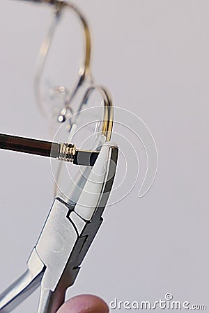 Adjusting inclination of temples on modern metal eyeglass frame with conical inclination pliers Stock Photo