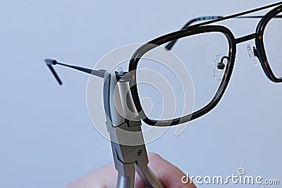 Adjusting inclination of temples on modern plastic and metal eyeglass frame with conical inclination pliers Stock Photo