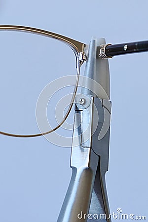 Adjusting inclination of temples on modern plastic and metal female eyeglass frame with conical inclination pliers Stock Photo