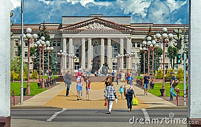 Administrative building with stucco on the facade against the background of walking people on the alley with benches and Editorial Stock Photo