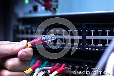 Administrator Hand with network cables connected to servers in datacenter Stock Photo