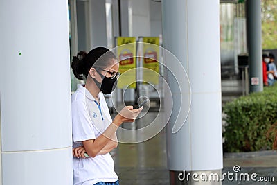 Adolescent girls wearing glasses with hygienic mask and stand using a mobile phone Editorial Stock Photo