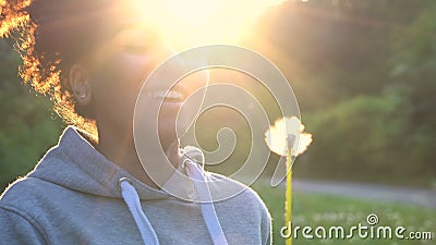 Adolescente afroamericano o giovane donna della ragazza della corsa mista che ride, sorridente e soffiante un dente di leone al t video d archivio Adolescente afroamericano o giovane donna della ragazza della corsa mista che ride, sorridente e soffiante un dente di leone al t video d archivio