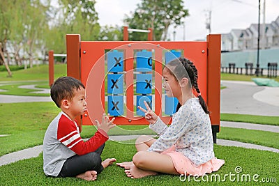 Adorable Asian little boy and young girl kid sitting in the garden playground with playing rock scissors paper game Stock Photo