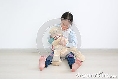 Adorable asian little child girl applying alcohol gel from plastic bottle for cleaning teddy bear hands for hygiene and anti virus Stock Photo