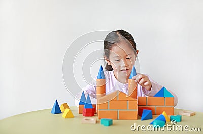 Adorable Asian little girl playing a colorful wood block toy on table over white background Stock Photo