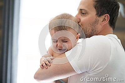 Adorable baby with father sonsoling close to the window Stock Photo