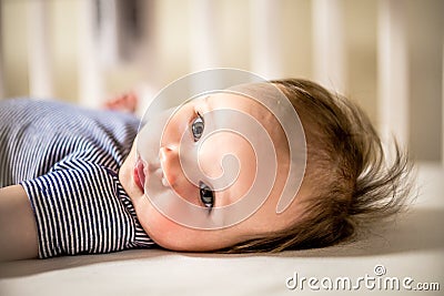 Adorable Baby Girl Lays in Crib Stock Photo